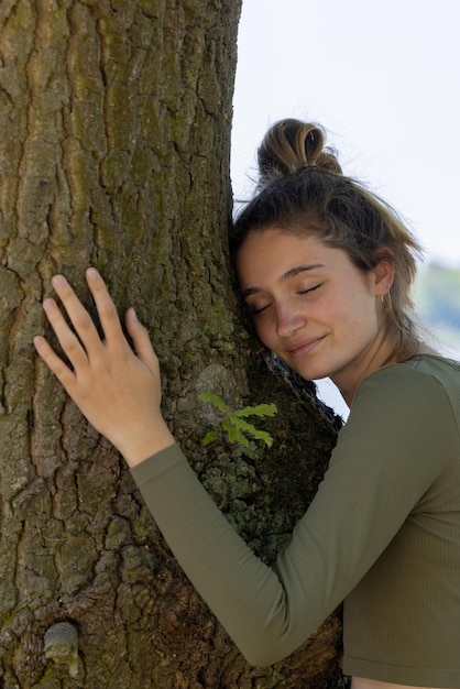 Foto vista lateral de una mujer joven de pie contra un árbol