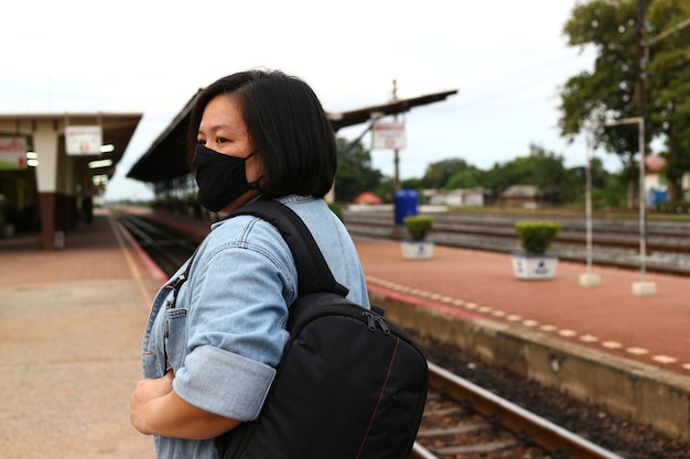 Vista lateral de una mujer joven de pie en la estación de tren