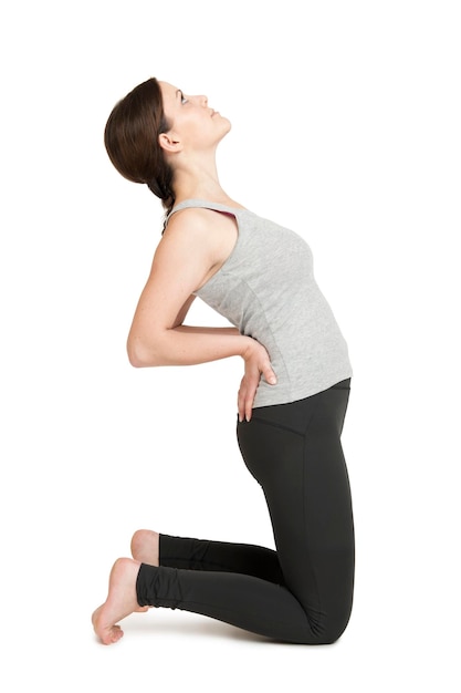 Vista lateral de una mujer joven practicando yoga sobre un fondo blanco