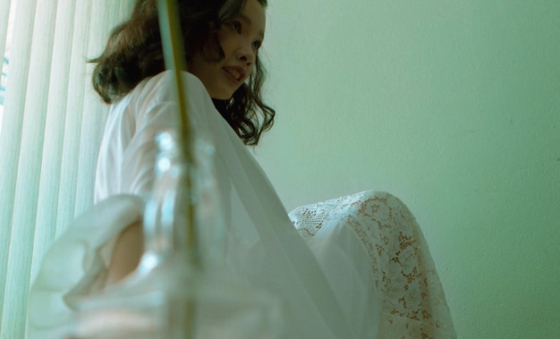 Foto vista lateral de una mujer joven sentada en una pared blanca