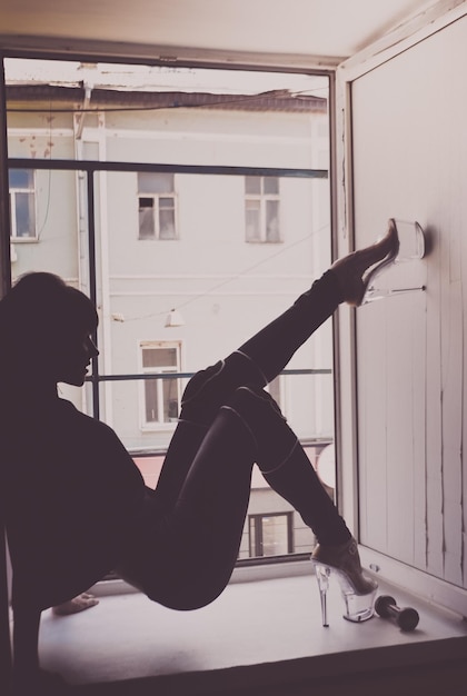 Foto vista lateral de una mujer joven sentada en la ventana