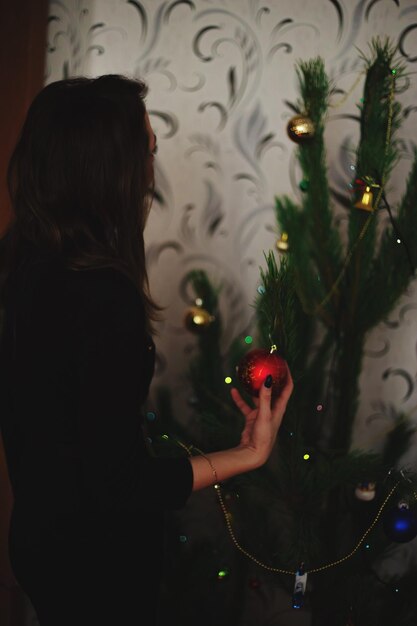 Vista lateral de una mujer joven sosteniendo una joya de Navidad