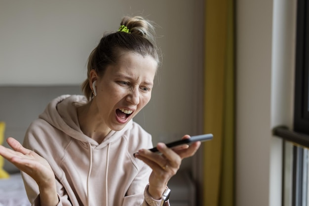 Vista lateral de una mujer joven usando el teléfono móvil en casa