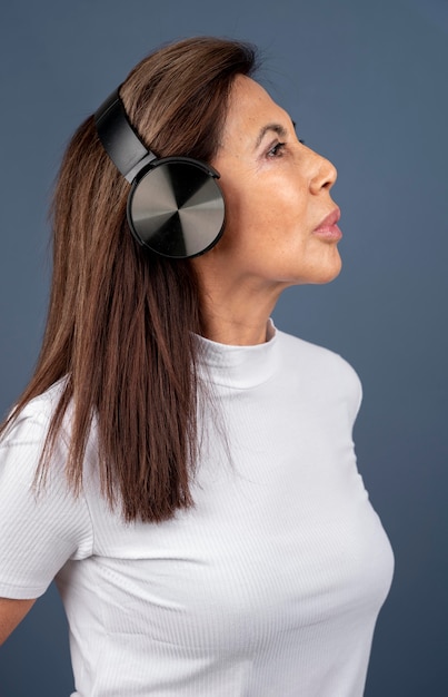 Foto vista lateral de la mujer mayor escuchando música a través de auriculares