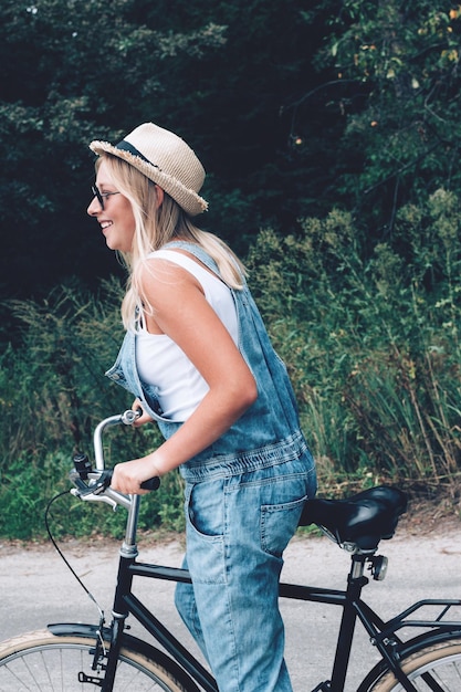 Foto vista lateral de una mujer montando una bicicleta contra los árboles en el bosque