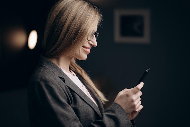 Vista lateral de una mujer de negocios sonriente usando un teléfono inteligente