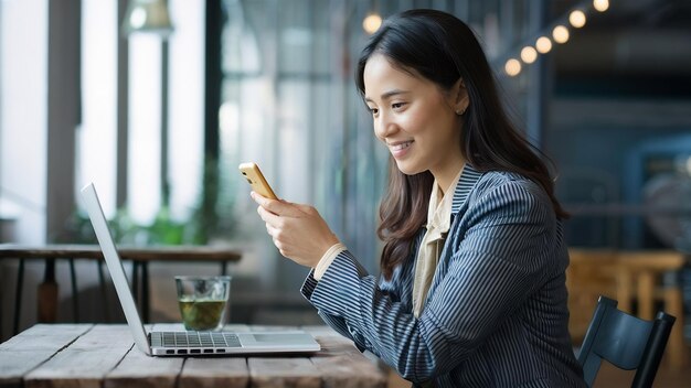 Vista lateral de una mujer de negocios con teléfono inteligente y portátil