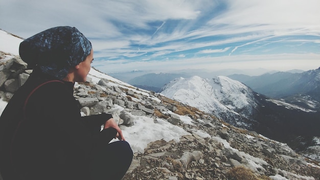 Vista lateral de una mujer en un paisaje de montaña contra el cielo