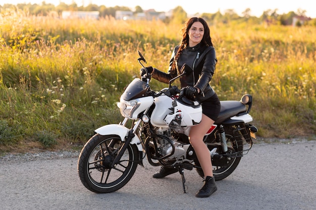 Foto vista lateral de la mujer posando sentada en su motocicleta