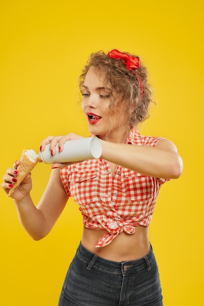 Foto vista lateral de la mujer presionando crema batida en cono de galleta