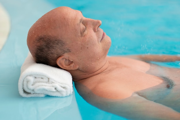 Foto vista lateral de una mujer relajándose en la piscina