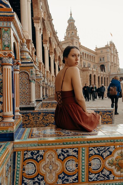 Foto vista lateral de una mujer sentada en un edificio en la plaza de sevilla - plaza de españa