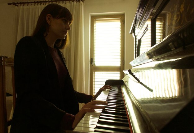 Foto vista lateral de una mujer tocando el piano en casa