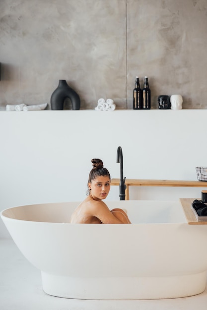 Vista lateral de una mujer tomando un baño de espuma en casa