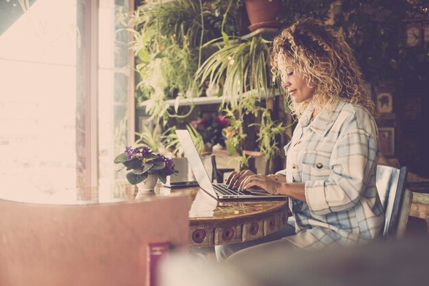 Foto vista lateral de una mujer usando una computadora portátil en una cafetería