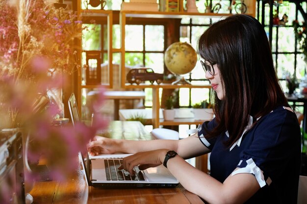 Vista lateral de una mujer usando una computadora portátil en la mesa