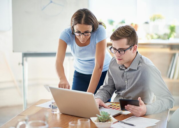 Vista lateral de una mujer usando una computadora portátil mientras está sentada en la mesa