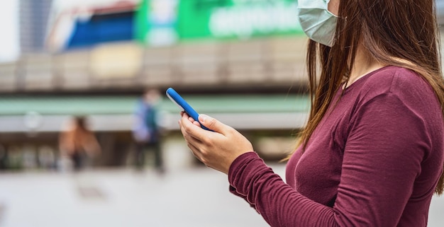 Vista lateral de una mujer usando un teléfono móvil en la ciudad