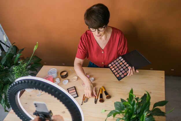 Vista lateral de una mujer usando el teléfono móvil mientras está sentada en la mesa