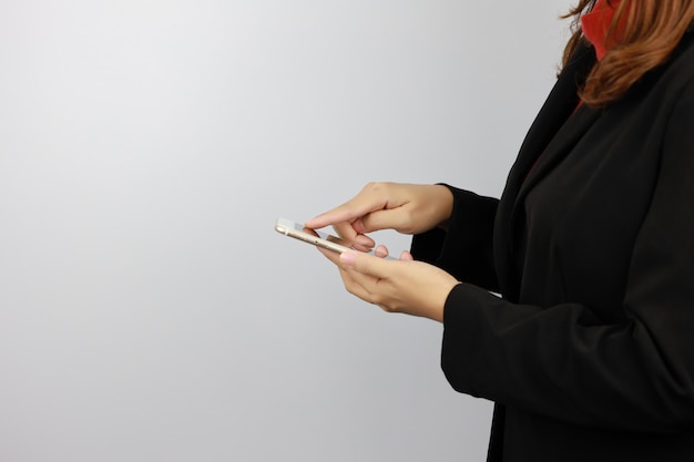 Vista lateral mulher de negócios vestindo uniforme preto e vermelho terno segurando e tocando o telefone móvel com confiante