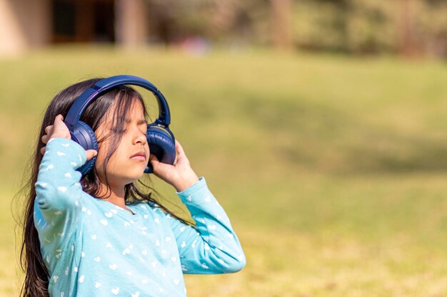 Vista lateral de una niña con auriculares mientras está sentada en tierra