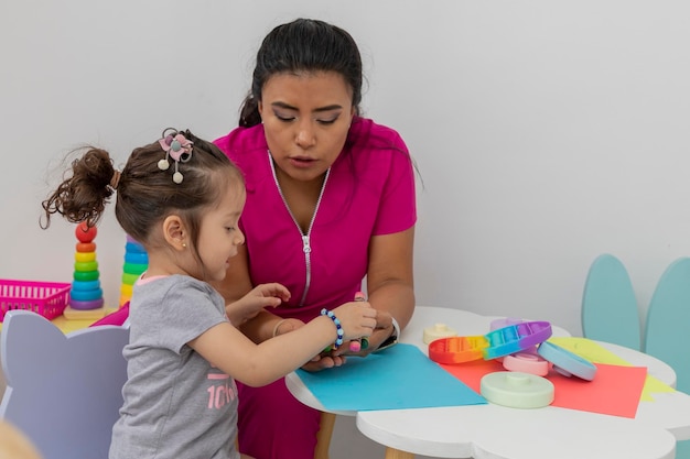 Vista lateral de una niña dibujando con una pediatra en su oficina