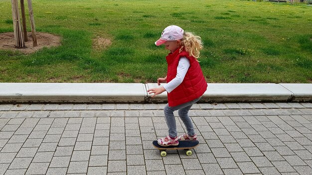 Foto vista lateral de una niña haciendo skateboard en un sendero