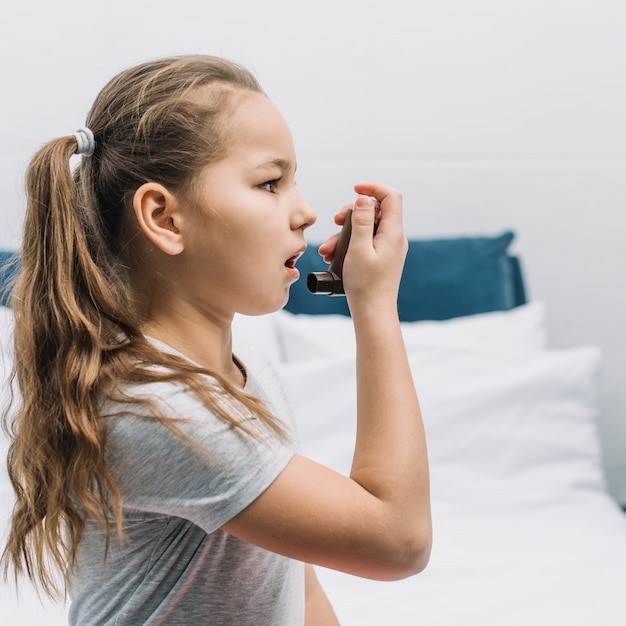 Foto vista lateral de una niña con inhalador de asma