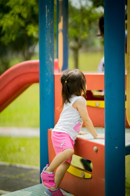 Foto vista lateral de una niña jugando en el patio de recreo