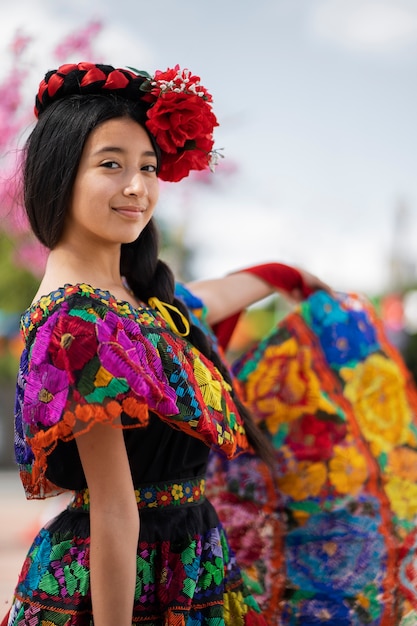 Foto vista lateral niña sonriente con vestido tradicional