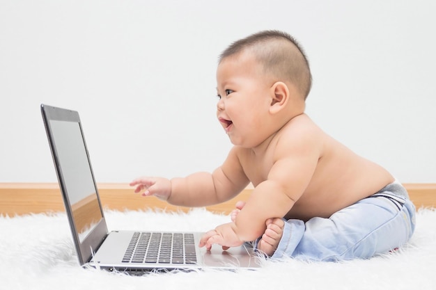 Vista lateral de un niño sin camisa usando una computadora portátil en piel en casa