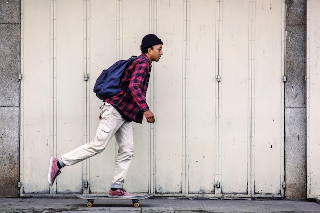 Vista lateral de un niño patinador montado en patineta en la calle peatonal