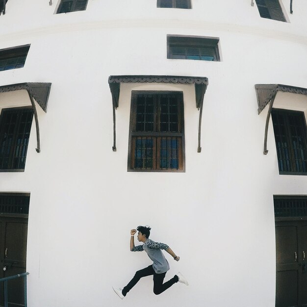 Foto vista lateral de un niño saltando contra edificios en la ciudad