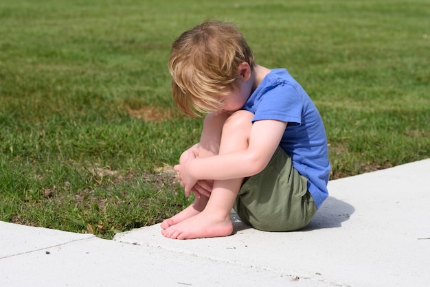 Foto vista lateral de un niño sentado en tierra