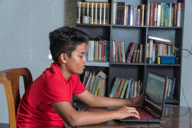 Vista lateral de un niño usando una computadora portátil en la mesa en casa