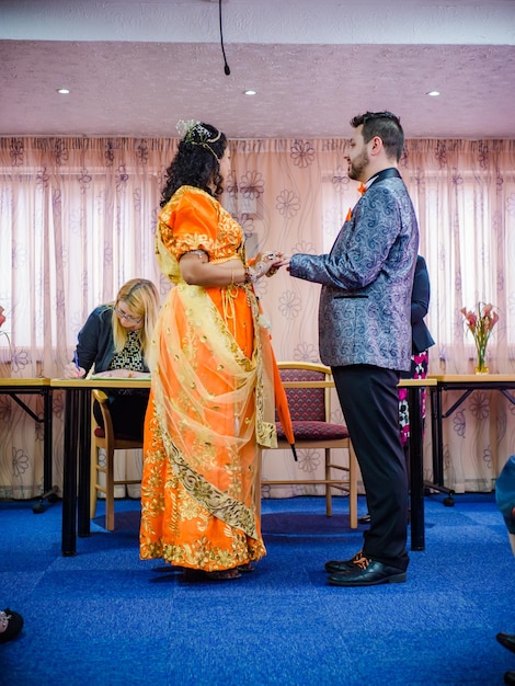 Foto vista lateral de la novia y el novio de pie en el suelo durante la ceremonia de la boda