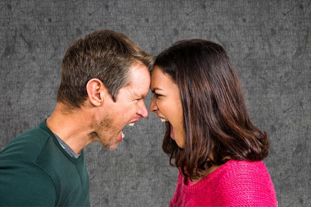 Vista lateral de la pareja gritando mientras lucha contra el fondo gris