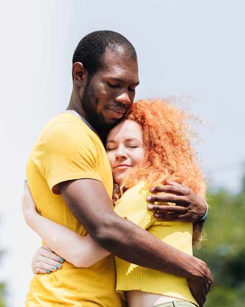 Foto vista lateral de la pareja interracial abrazándose