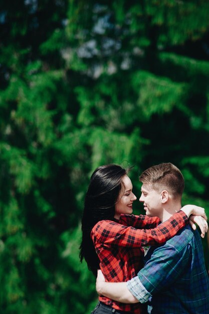 Foto vista lateral de una pareja joven de pie cara a cara en el bosque