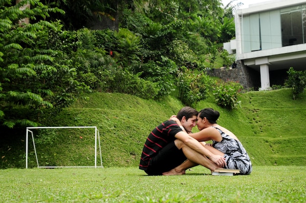 Vista lateral de una pareja romántica abrazándose mientras está sentada en un terreno cubierto de hierba
