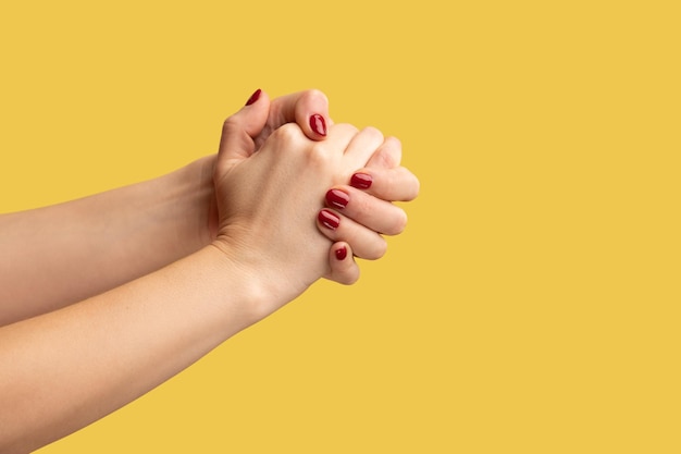 La vista lateral del perfil de primer plano de las palmas de las mujeres derecha e izquierda están conectadas en soporte de bloqueo y unión Foto de estudio interior aislada sobre fondo amarillo