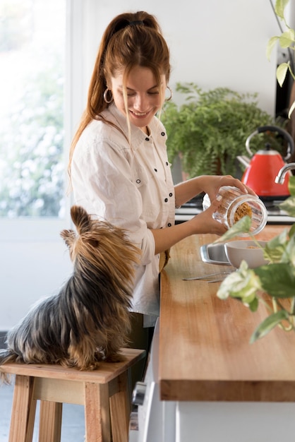 Foto vista lateral del perro de ingenio mujer al lado en la cocina