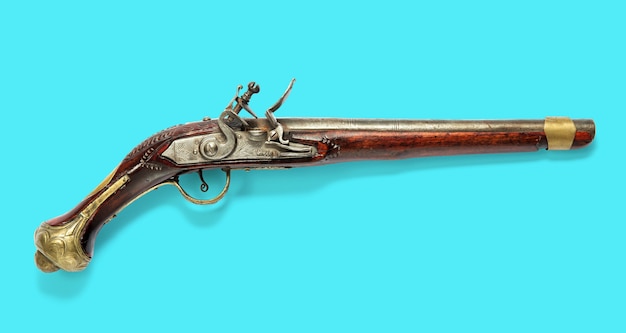 Vista lateral de una pistola de chispa de madera antigua de un solo cañón con mecanismo plateado sobre un azul