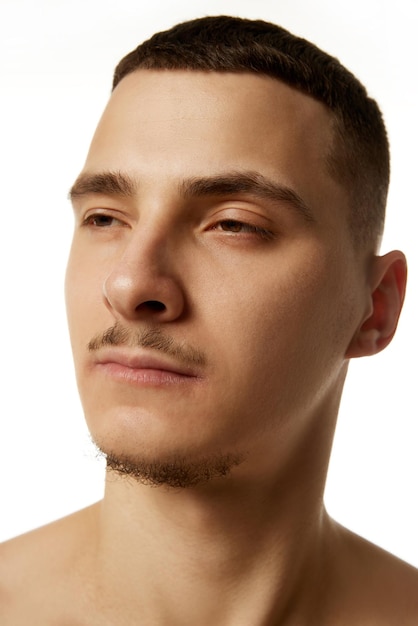 Vista lateral de primer plano de un hombre sin camisa con una barba recortada mirando hacia otro lado con expresión neutral