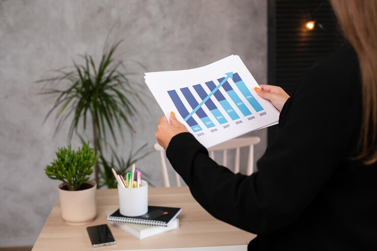 Vista lateral de primer plano de la mano de la mujer que analiza gráficos y diagramas gráficos de crecimiento estadístico