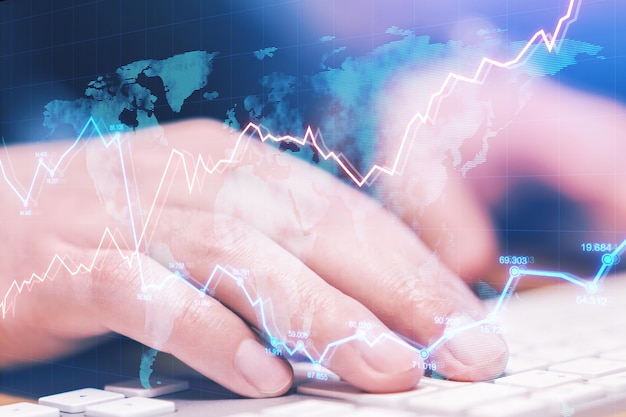 Vista lateral y primer plano de las manos usando el teclado de la computadora en el escritorio con gráfico de forex abstracto Concepto de comercio e intercambio de datos de Fintech Doble exposición