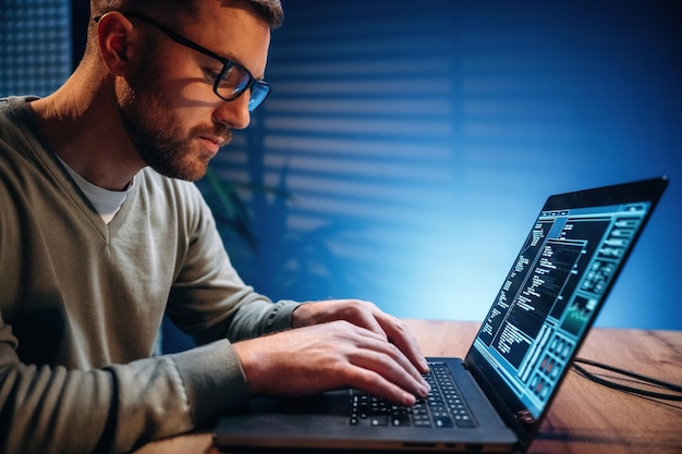 Vista lateral Programador masculino trabajando en el interior con una computadora portátil