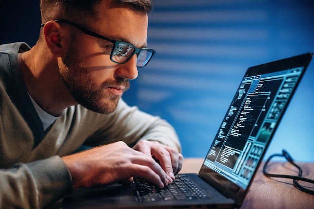 Vista lateral Programador masculino trabajando en el interior con una computadora portátil