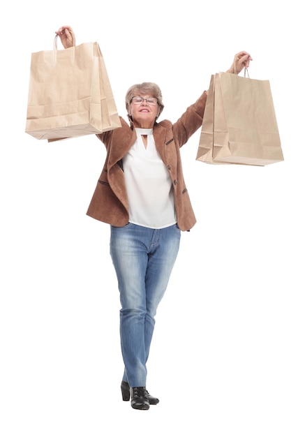 Vista lateral retrato de corpo inteiro de uma mulher sênior andando com sacolas de compras