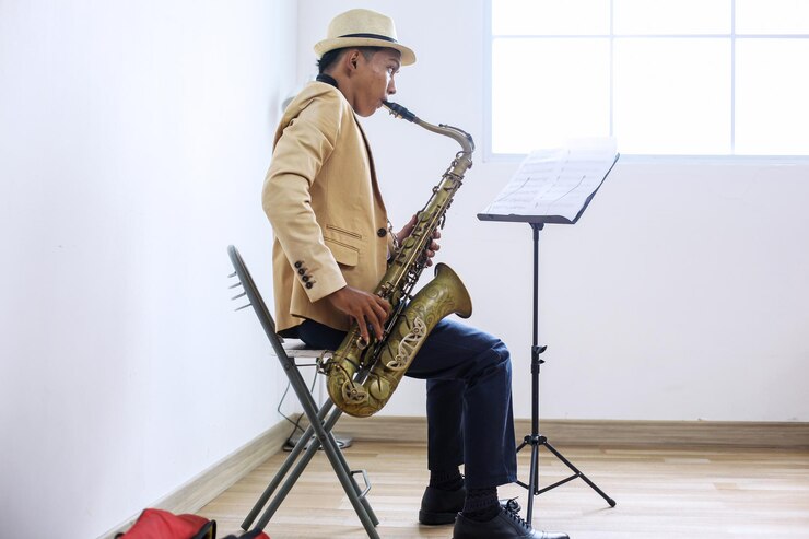 Foto vista lateral de un saxofonista practicando el saxofón mientras mira las notas musicales en el soporte en casa